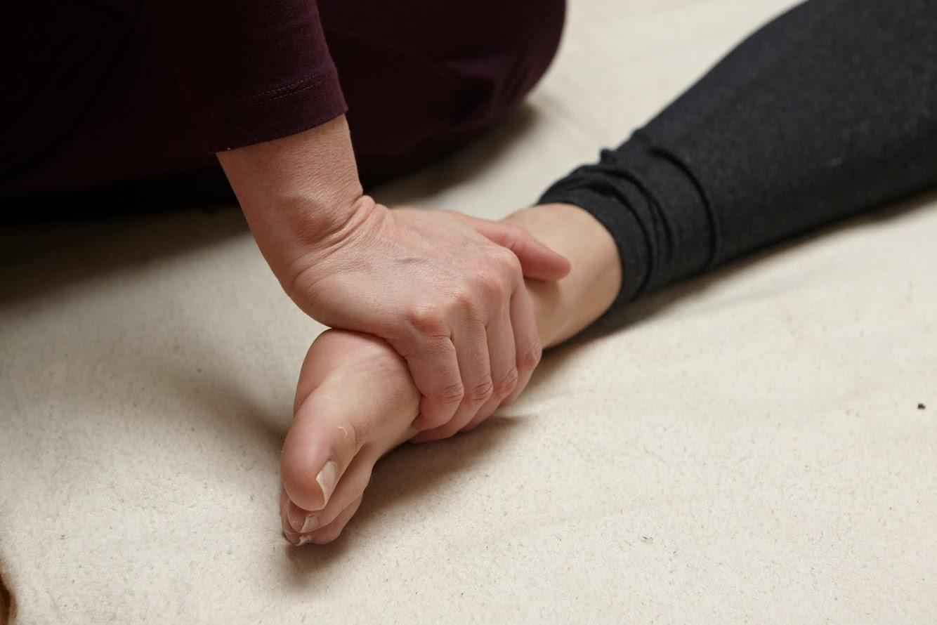 Two hands holding a client's forearm and wrist against white cloth